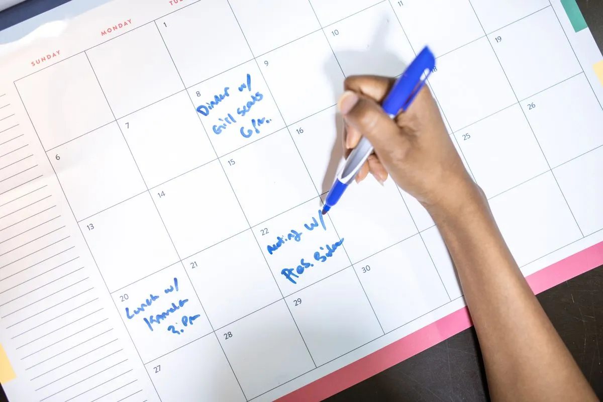A hand writing a habit plan into a monthly calendar, because staying consistent is a design problem, not a willpower contest