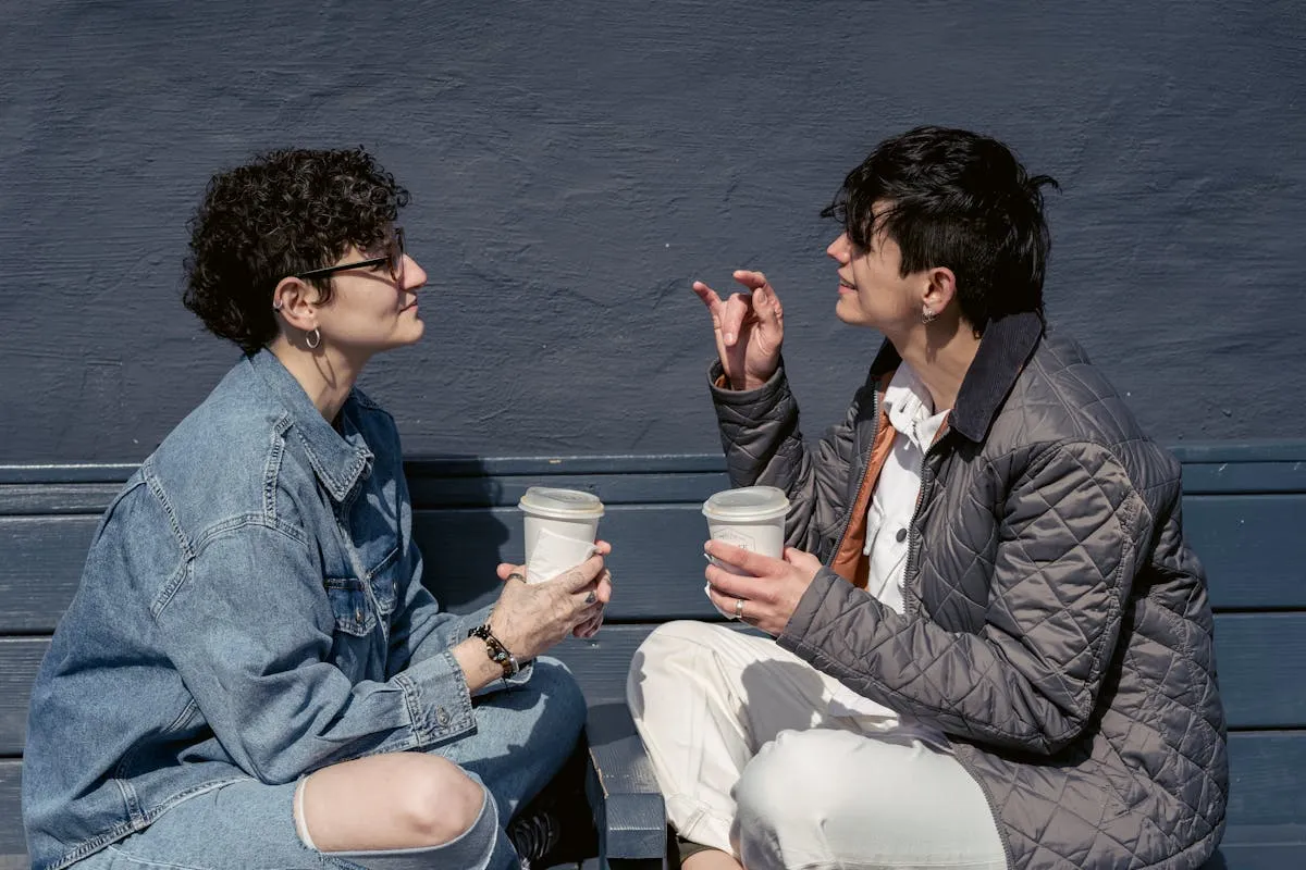 Two friends relaxing outdoors with coffee in the sun, a genuinely restorative option for a dopamine menu
